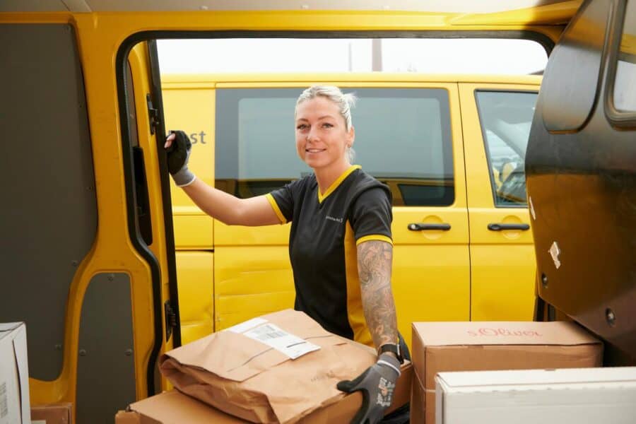 Effizienz auf der letzten Meile durch Paketlieferung von Postbotin aus dem Postauto außer Haus